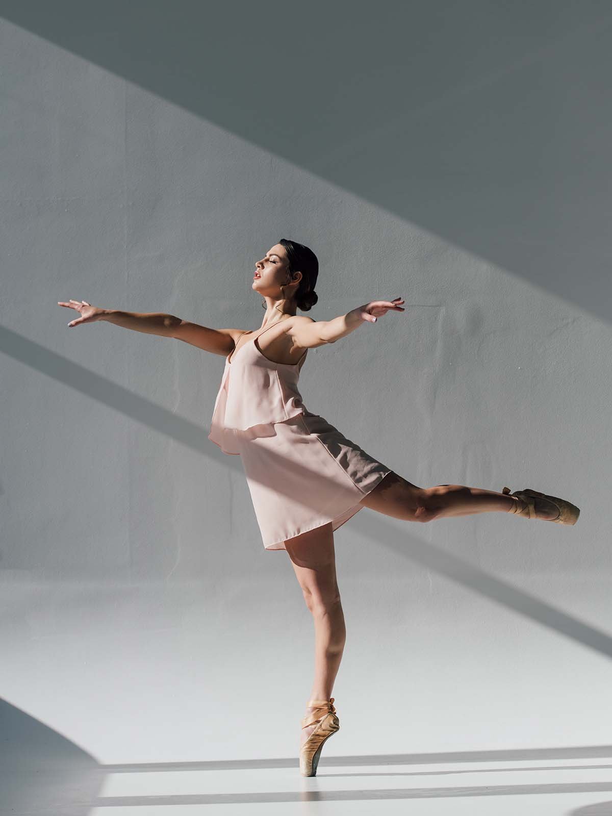 young ballerina dancing in pink dress and pointe shoes